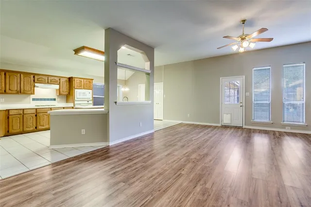 a view of a kitchen with a sink wooden cabinets and a living room