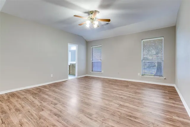 wooden floor in an empty room with a chandelier fan