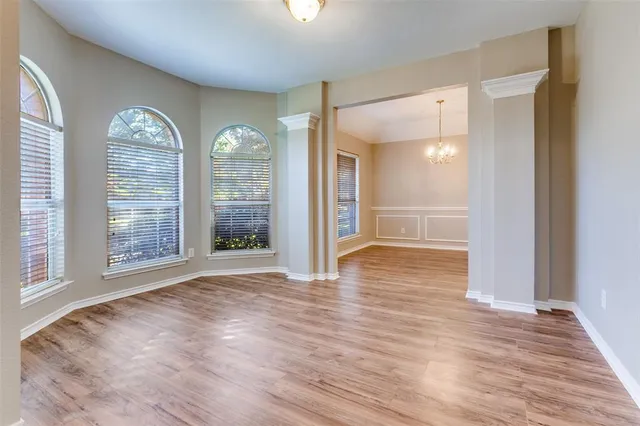 a view of an empty room with window and wooden floor