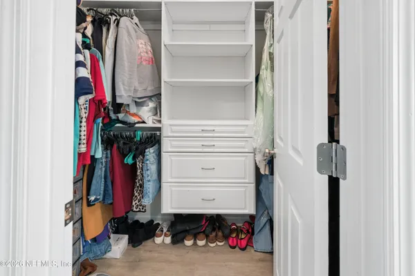 a view of walk in closet with clothes and shoes