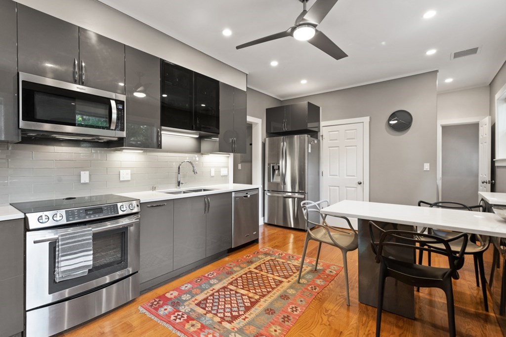 102 Addington Road, Unit 2 Brookline, MA 02445 - Photo 16 of 30 a kitchen with stainless steel appliances kitchen island granite countertop a stove top oven a sink dishwasher a dining table and chairs with wooden floor