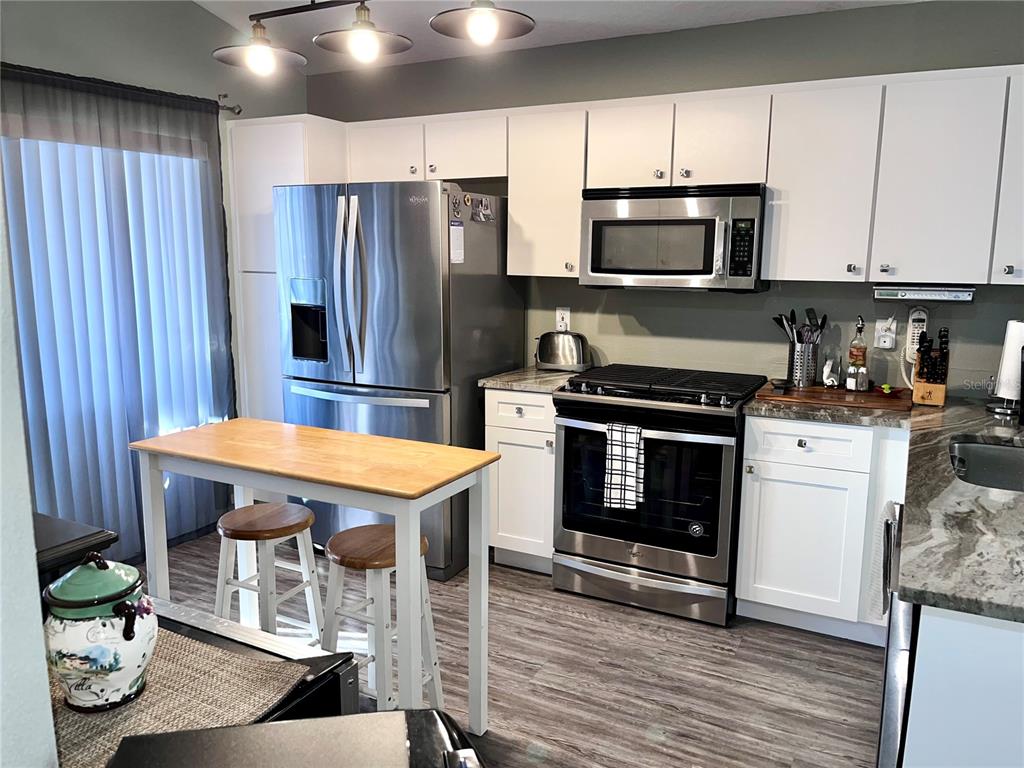 8620 Persea Court New Port Richey, FL 34655 - Photo 5 of 14 a kitchen with stainless steel appliances kitchen island granite countertop a stove a sink dishwasher and a microwave oven with cabinets