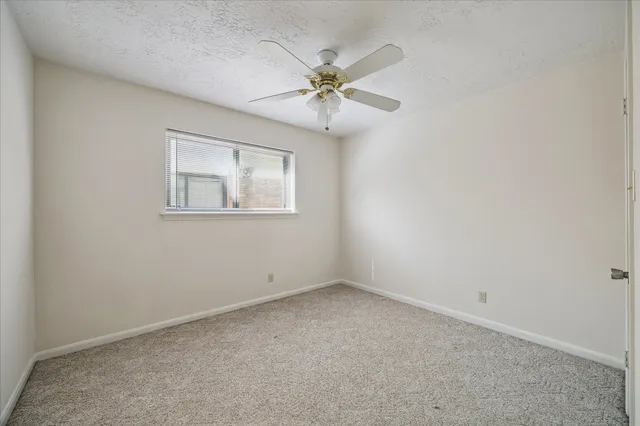 an empty room with a window and a fan