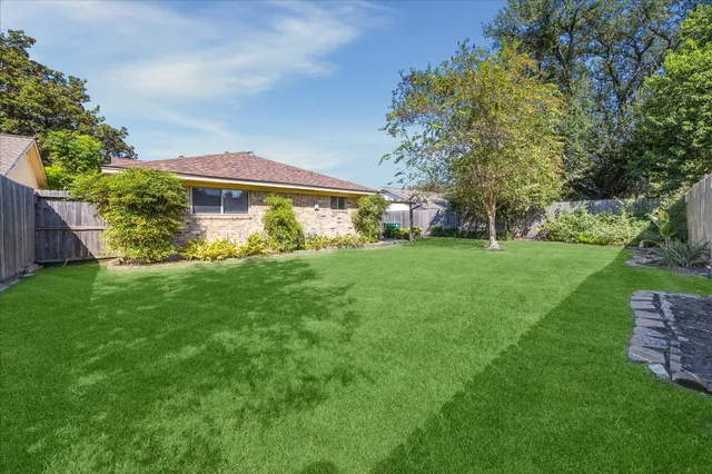 a view of a house with a big yard potted plants and large tree