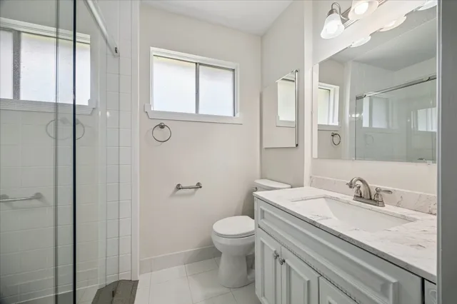 a bathroom with a granite countertop sink a toilet and shower