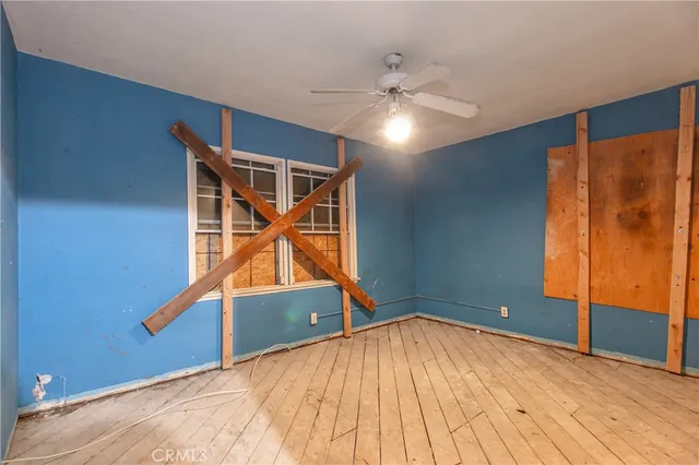 an empty room with wooden floor and fan
