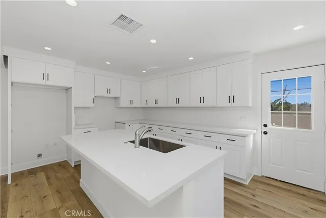 a kitchen with a sink a stove a refrigerator and white cabinets