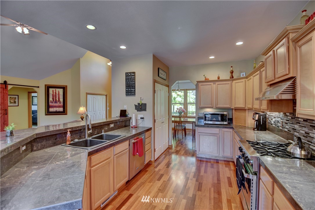 15837 Case Road Southwest Rochester, WA 98579 - Photo 7 of 40 a large kitchen with stainless steel appliances granite countertop a stove top oven a sink dishwasher a dining table and chairs with wooden floor