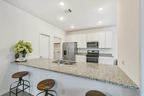 a kitchen with stainless steel appliances granite countertop a sink and a refrigerator