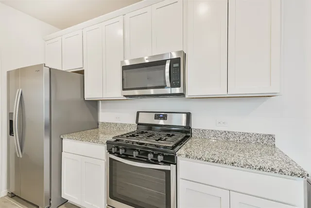 a kitchen with granite countertop white cabinets and stainless steel appliances