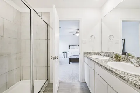 a spacious bathroom with a granite countertop sink a mirror and shower