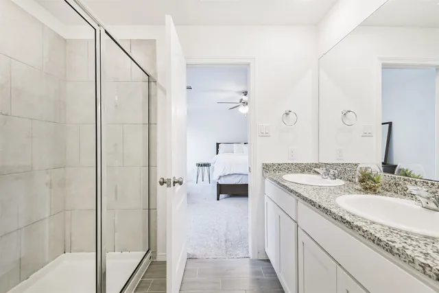 a spacious bathroom with a granite countertop sink a mirror and shower