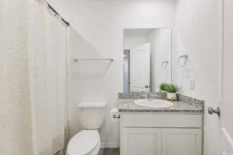 a bathroom with a granite countertop sink toilet and mirror