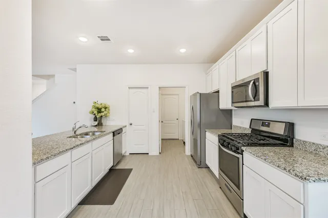 a kitchen with stainless steel appliances granite countertop a sink stove and refrigerator