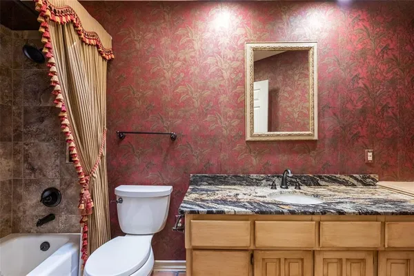 a bathroom with a granite countertop toilet and a sink