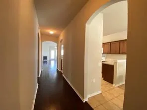a view of a hallway with wooden floor and a bathroom