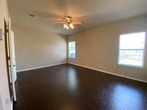 an empty room with wooden floor and windows