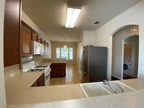 a kitchen with stainless steel appliances kitchen island granite countertop a refrigerator and a sink