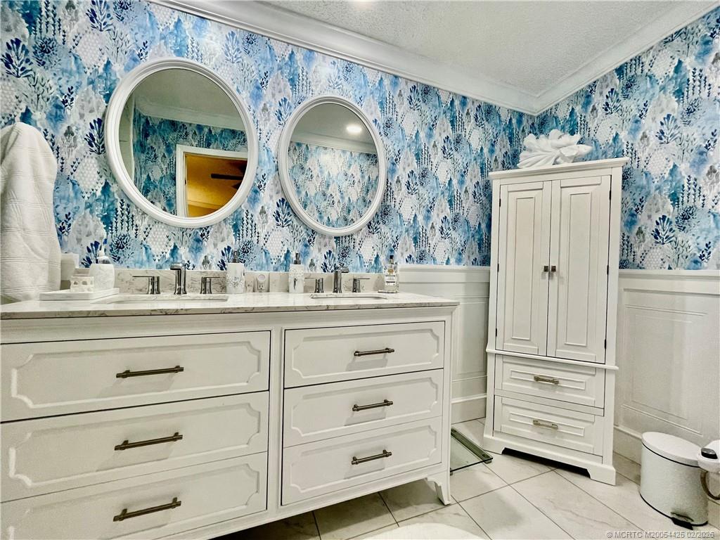 14513 Southwest Rake Drive Indiantown, FL 34956 - Photo 20 of 32 Wainscoting, vinyl wallpaper, dbl sinks, new shower tile & rain shower head, toilet w/bidet, linen closet, pot lights & vinyl flooring.