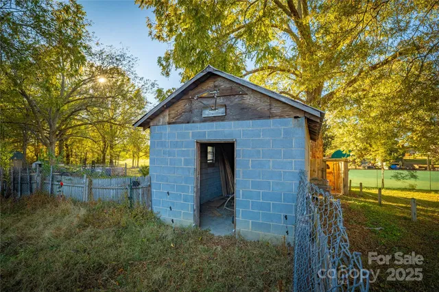 a view of a brick house with a large tree and wooden fence