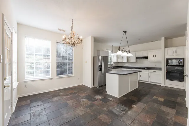 a kitchen with kitchen island granite countertop a stove a sink a center island a stove and a window