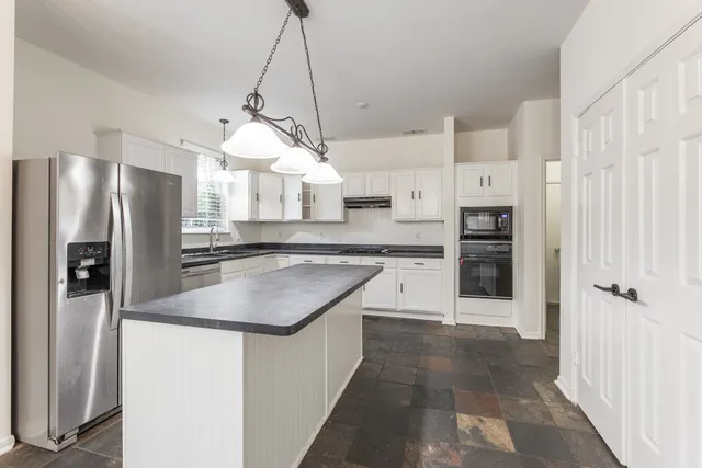 a kitchen with stainless steel appliances granite countertop a refrigerator a sink and a stove