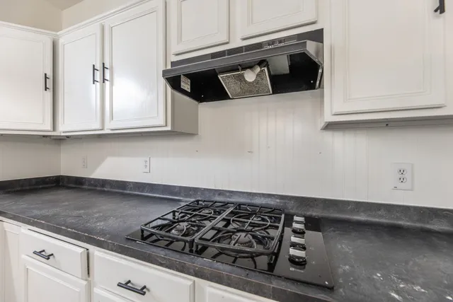 a kitchen with granite countertop white cabinets and a stove