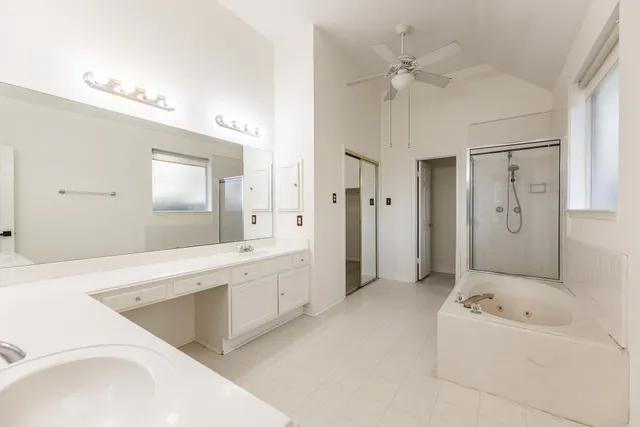 a spacious bathroom with a tub sink shower and mirror