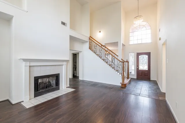 a view of an empty room with wooden floor fireplace and a window