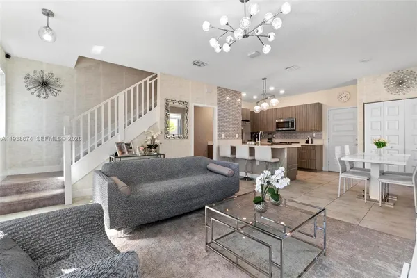 a living room with furniture kitchen view and a chandelier