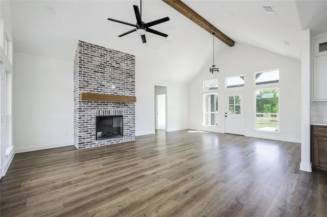 an empty room with windows fireplace and wooden floor