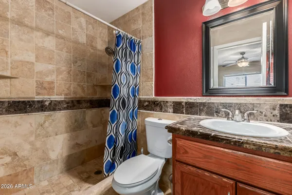 a bathroom with a granite countertop sink a toilet and a mirror