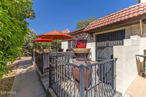 a view of a patio with table and chairs under an umbrella with wooden fence
