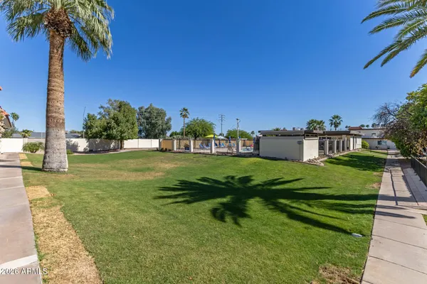 a view of a white house in a big yard with palm trees