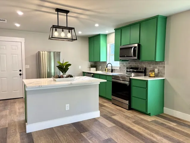 a kitchen with kitchen island stainless steel appliances a sink cabinets and wooden floor