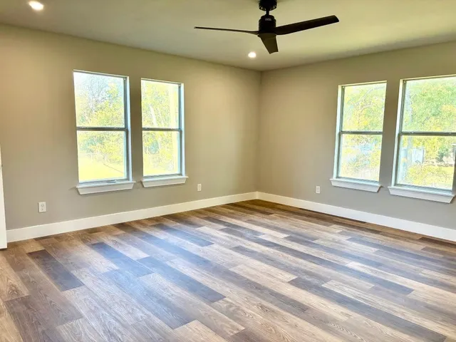 a view of empty room with wooden floor and fan