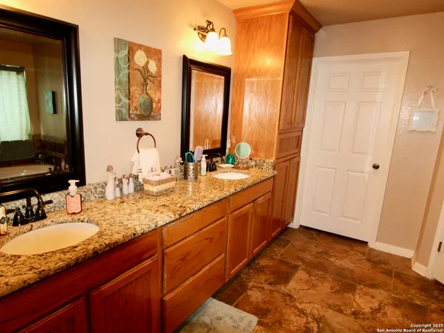 a bathroom with a granite countertop double vanity sink and a mirror