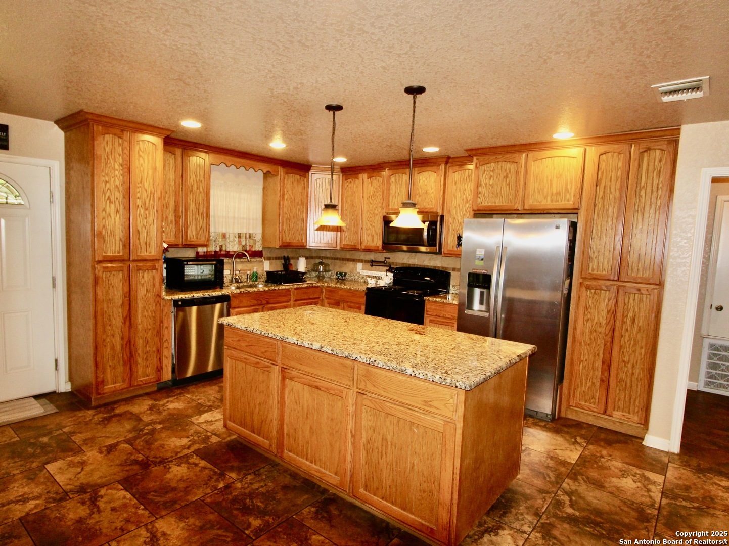 12365 Rudolph Road, Unit 3 Atascosa, TX 78002 - Photo 8 of 42 a large kitchen with stainless steel appliances kitchen island granite countertop a refrigerator a sink a stove and island