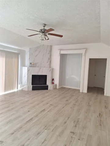 a view of empty room with a fireplace and ceiling fan