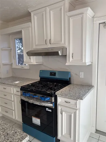 a kitchen with granite countertop white cabinets and a stove
