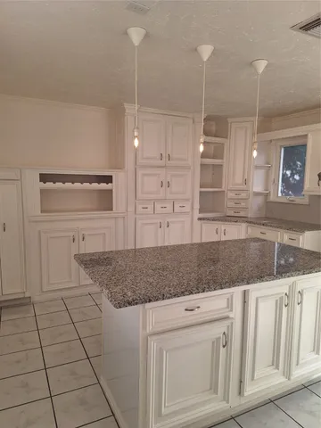 a kitchen with granite countertop white cabinets and a wooden floor