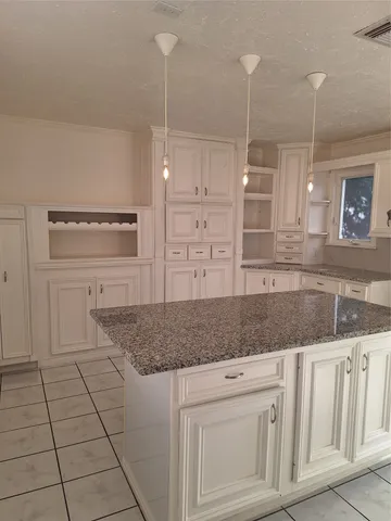 a kitchen with granite countertop white cabinets and a wooden floor