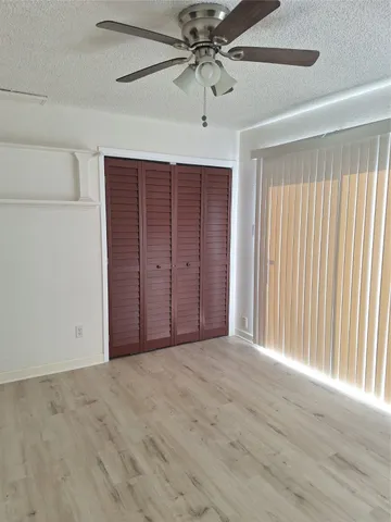 en empty room with windows and ceiling fan