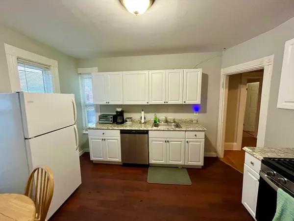 a kitchen with granite countertop a refrigerator stove top oven and sink