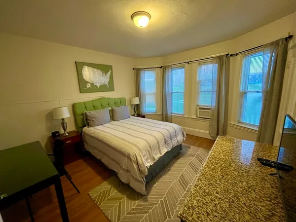 a bedroom with a bed and a dresser next to a window