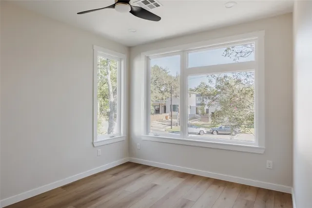 a view of an empty room with a window and wooden floor