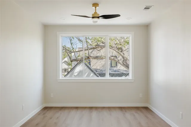 an empty room with a window and a ceiling fan