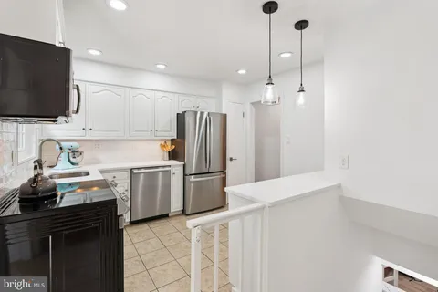 a kitchen with a sink a refrigerator and a stove top oven