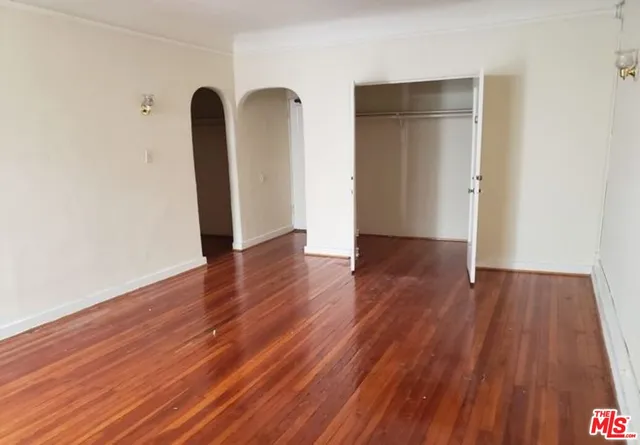 an empty room with wooden floor and glass door
