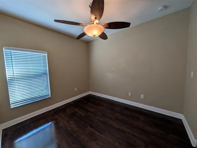 a view of an empty room with window and wooden floor